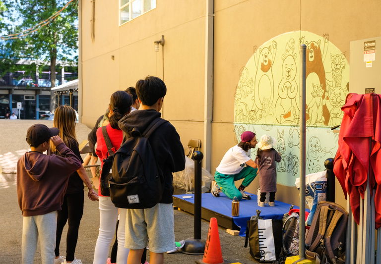 Film still from A Path to Survival. Pedram and community members paint their collective mural on Granville Island.