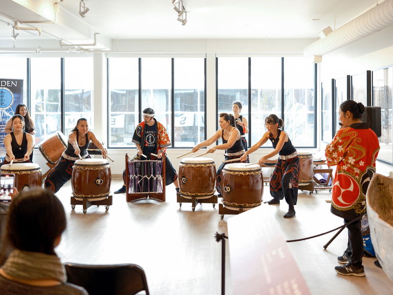 A class of people playing traditional Japanese drums.