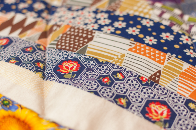 A closeup of a blanket with lots of different patterns with blue, white, red, orange and brown