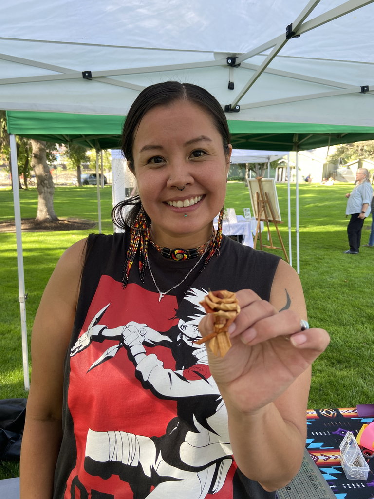 OKIB Knowledge Keeper Florence Fred shows a cedar rose which she created. She is wearing colourful traditional beaded earrings and necklace.