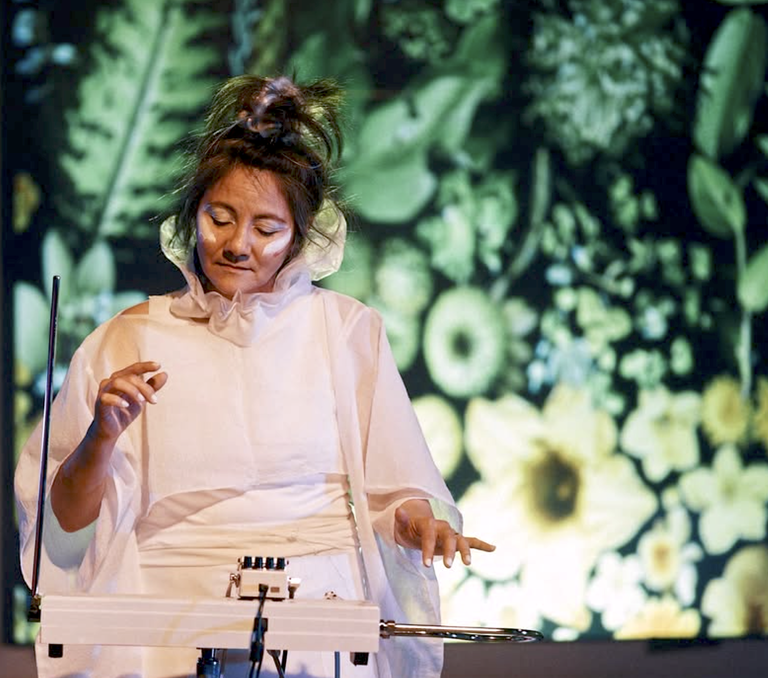 óFukami playing theremin on stage at Cluster Festival, with Joel Penner's projected visuals glowing behind her.