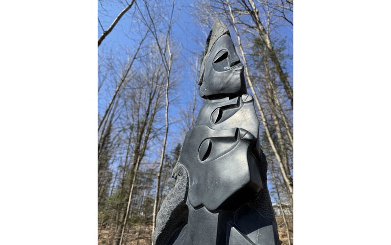 Springstone sculpture with carvings of Shona women's heads and faces, one above the other.