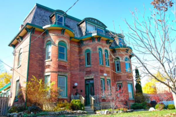 Large Second-Empire style red-brick house with green trim and shingles