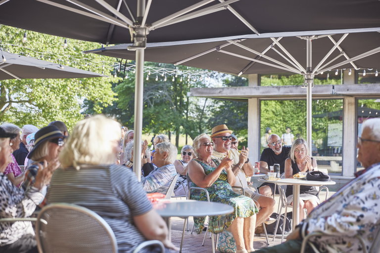 Patrons seated outside enjoying a performance.