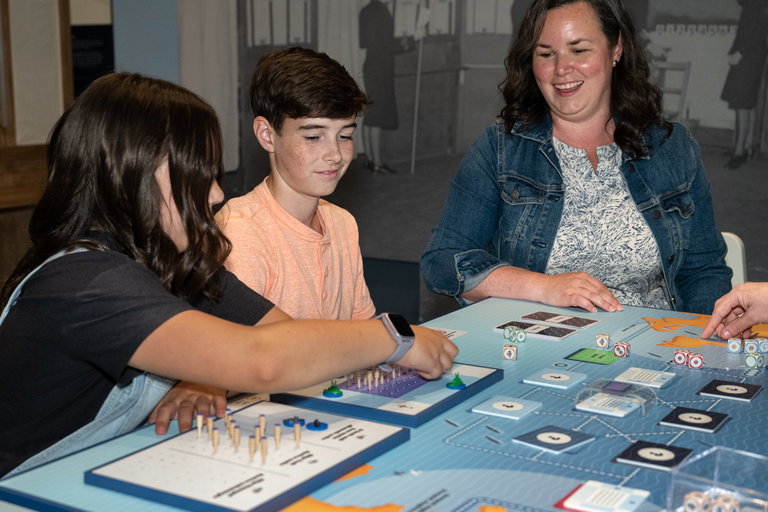 A close up of a family of three playing Atlantic Peril in the gallery.