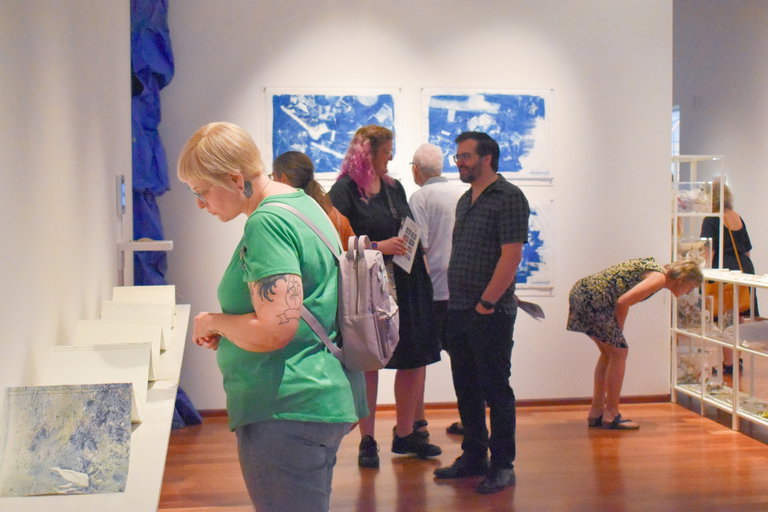 A group of people looking at different art works in a gallery setting.