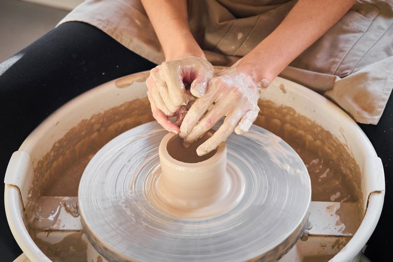 Image of hands working clay at potter's wheel