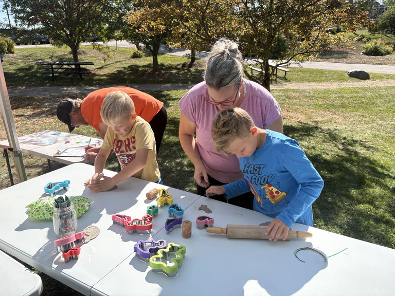 Two children using clay and cookie cutters to make designs outdoors with their parents