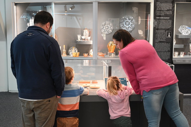 Family of two adults and two children looking at cases in the glass gallery