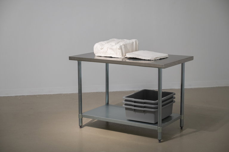 a plaster-cast luggage placed on stainless steel table with grey trays