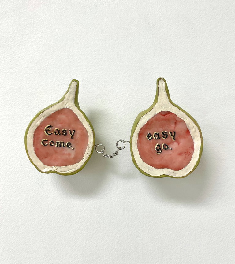 Inside a fig cut in half, chained together with the text in one Easy Come and the other side says Easy Go