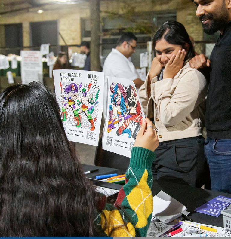 Coloring book pages featuring original wrestler illustrations designed by PH1 Studios, displayed on a table at 401 Richmond during Nuit Blanche for a live community art activity.