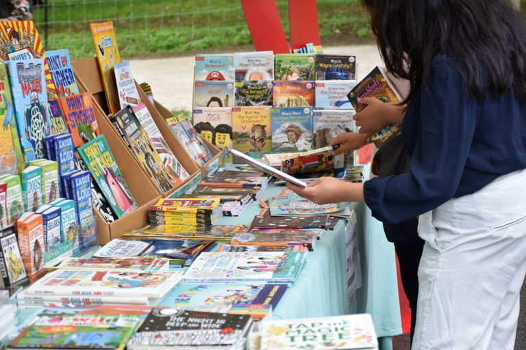 Two people peruse a table filled with children's books.
