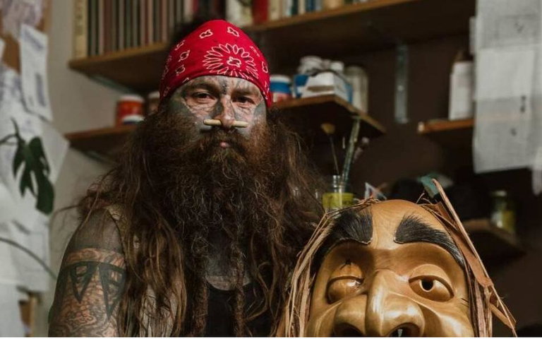 Gordon Sparks holding a hand-carved wooden mask.