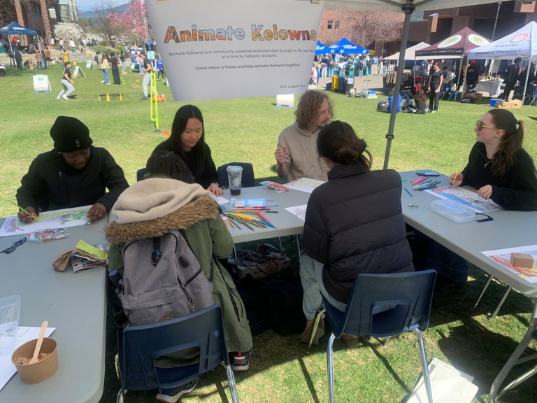 Adults working at a table using markers to colour design frame pages