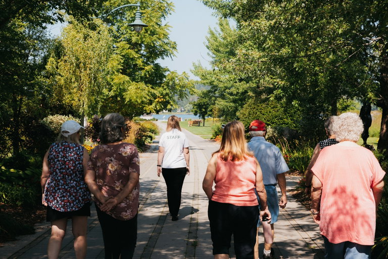 A guided group walk along a tree-lined waterfront trail.
