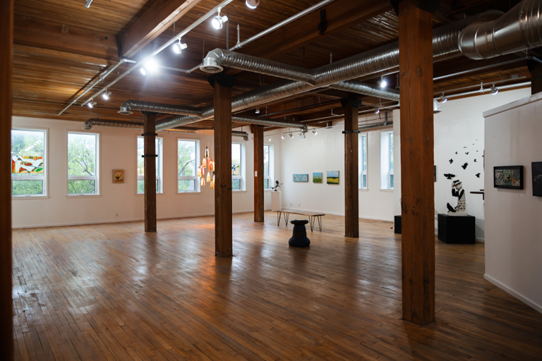 A large gallery space room with art on the walls around it