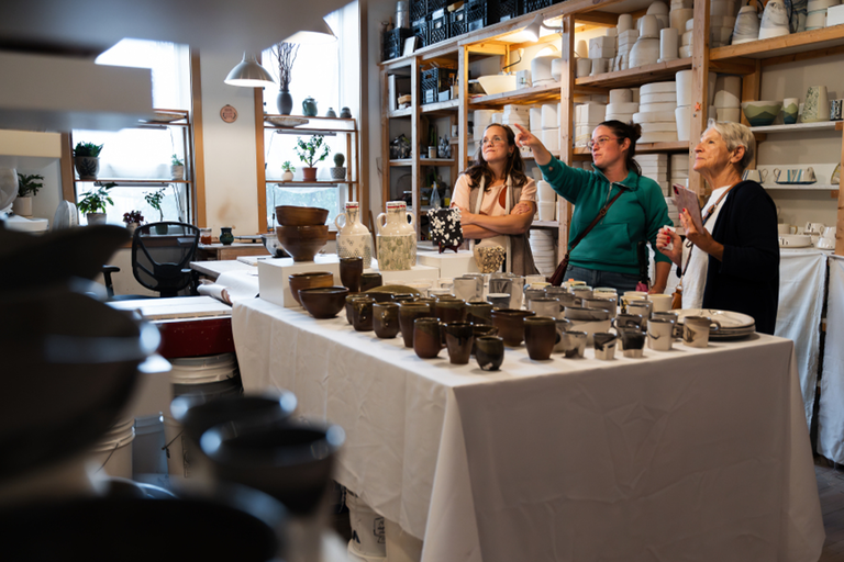 An art studio filled with pottery and three woman looking across the room