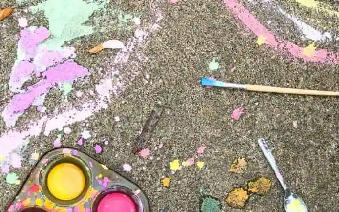 Image is of chalk paint in lots of colours against a sidewalk background.