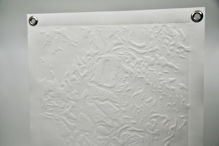 “Inkblot No. 1 print” by Olivia Brouwer. A white sheet of Stonehenge paper is embossed using a carved wood block and a printing press. The image is taken from a painting from the artist’s early career, which is inspired by micro photographs of forest surfaces.