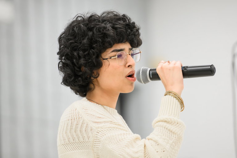 Youth artist with curly hair sings into microphone