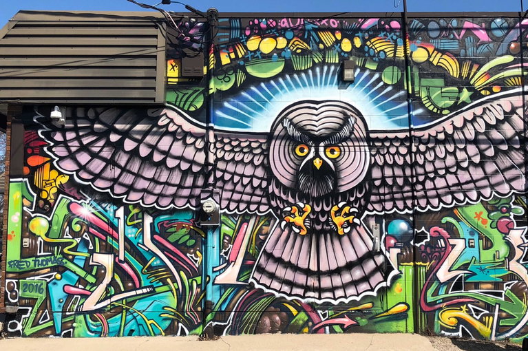 A mural of an owl painted onto the side of a brick building.