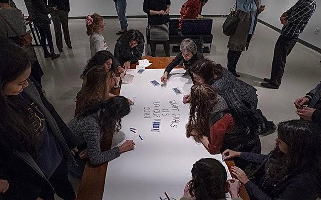 People drawing on poster sheet, interacting with art.
