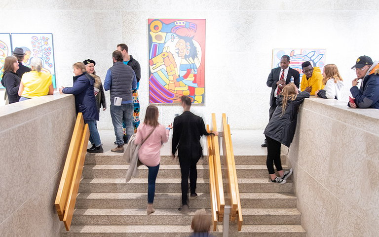 People walking up flights of stairs in a an art gallery.