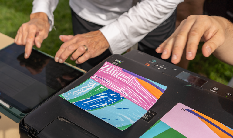 Close up of hands and a printer with mural tiles to be scanned.