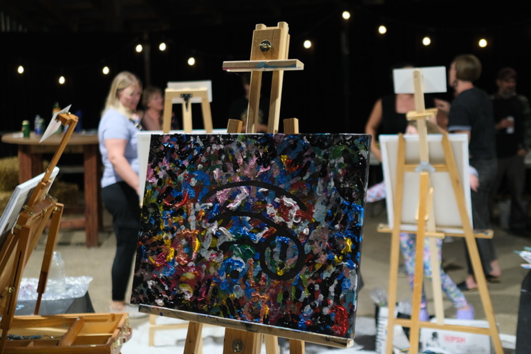 A close up of a painting on an easel in a large barn setting