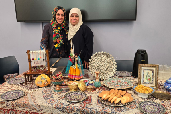 Two women stand behind a table full of cultural items