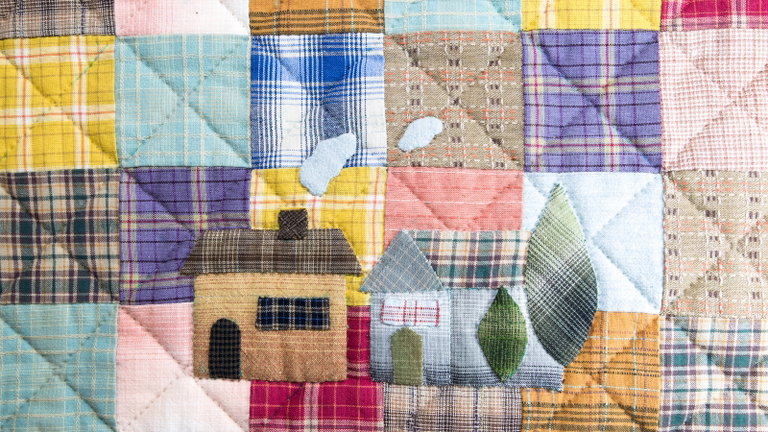 a patchwork quilt with a house and trees