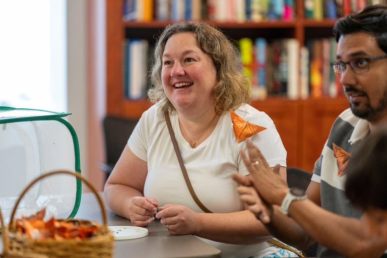 Two participants sitting at a craft table with paper butterflies pinned on their shirts.