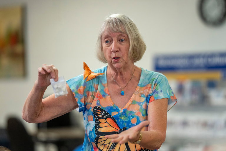 An instructor holding a package of materials to make mudmalls for monarch butterflies in her right hand.