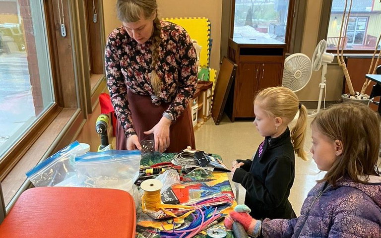 Photo of Trash Theatre leader helping two young girls at a creative workshop