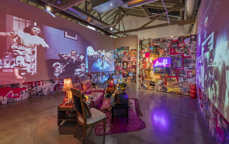 Tracey Snelling's exhibition showcasing a collage in the walls and some furniture in the middle of the room