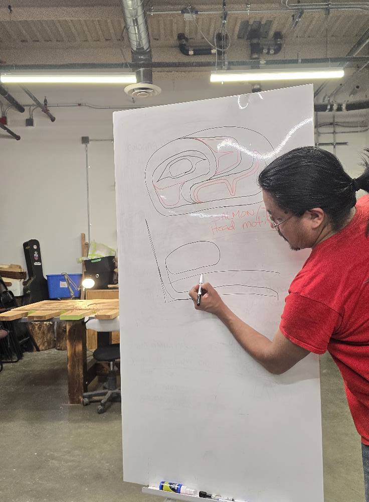 Duran Henry draws a Northwest Coast art form on white sheet.