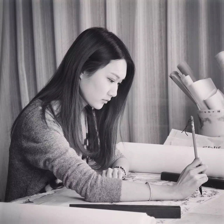 Artist focused on painting a traditional Chinese artwork with brush and rice paper