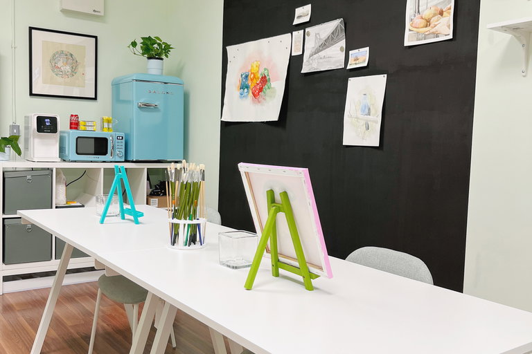 Cozy and well-equipped art studio setup with easels, brushes, and artworks on the wall