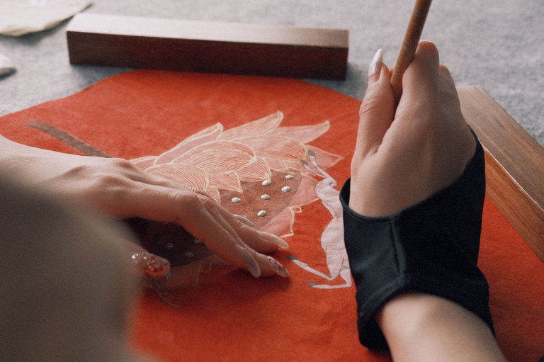 Close-up of an artist painting a lotus with traditional Chinese brush technique on rice paper
