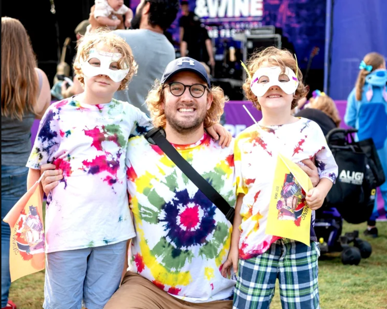 A family photo with two children in tye-dye shirts and a parent in the middle.