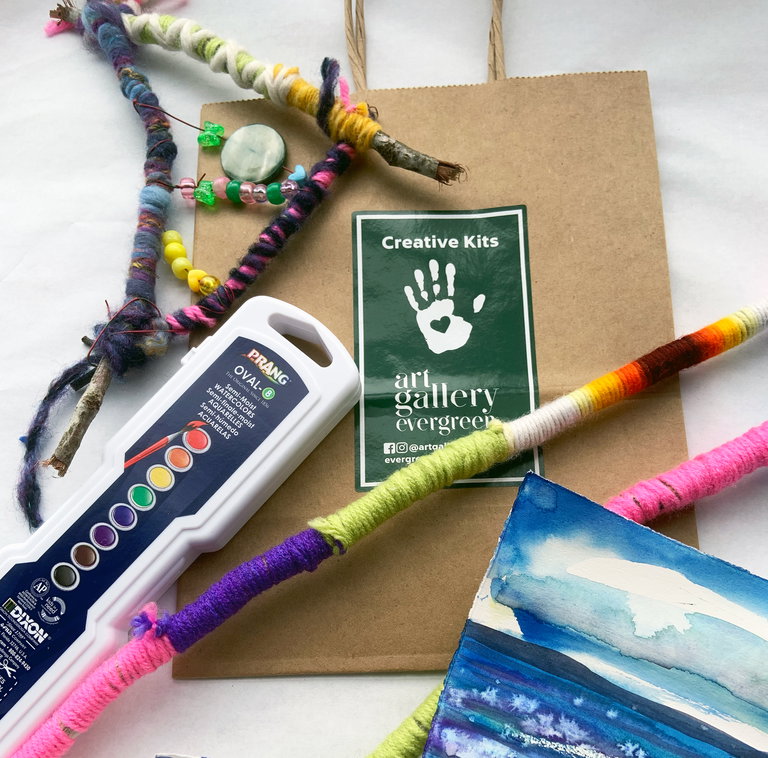 A photo of a Creative Kit and it's contents, including paints, yarn and beads.