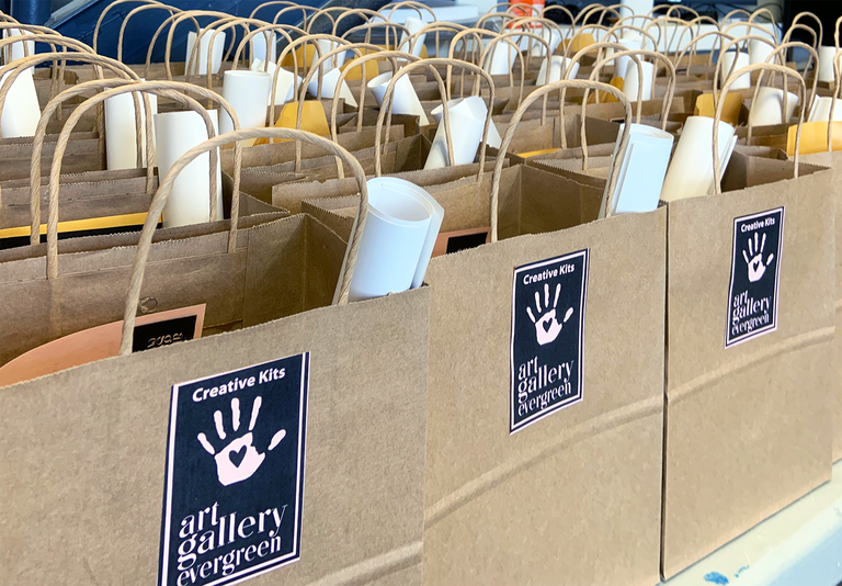 Many paper bags full of art supplies ready to go for Creative Kit giveaways!