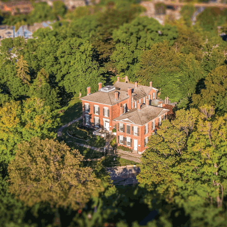 Aerial view of a red brick historic house surrounded by trees