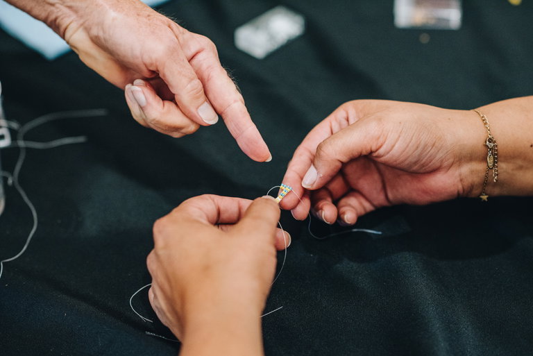 Close up of hands assembling coloured beads to make an earring