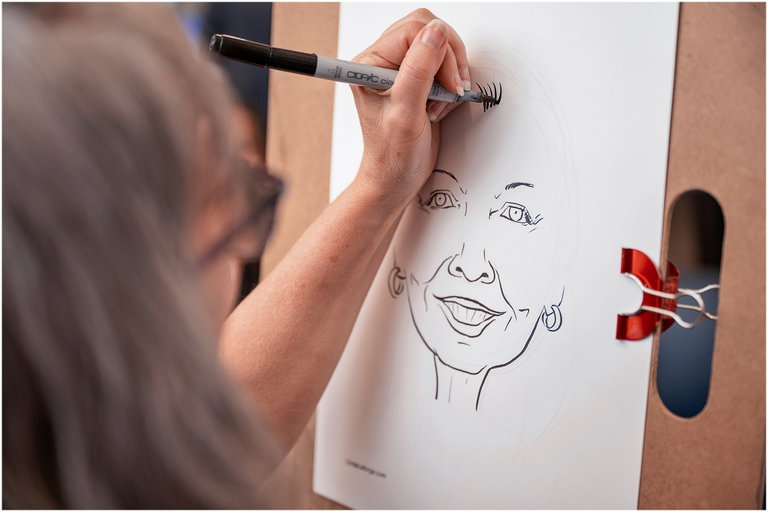 An artist is shown drawing a caricature portrait.