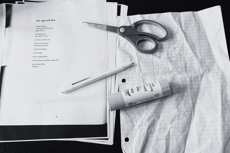 Black and white view of paper, a pen, and scissors placed on a desk. One piece of paper is printed documented with text. The poem pictured is called "the egg roll kid."